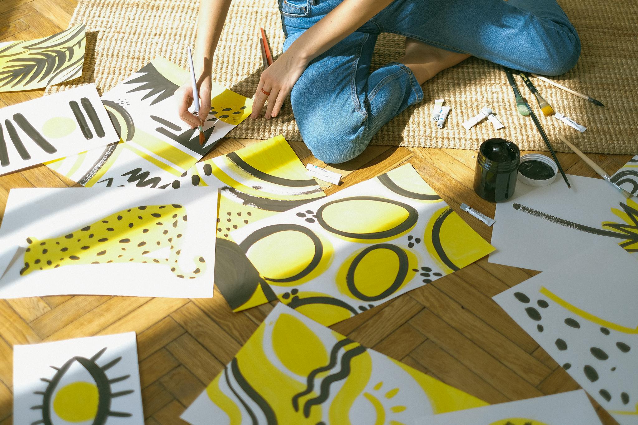 A vibrant display of abstract art creation with bright yellow and black designs on paper.