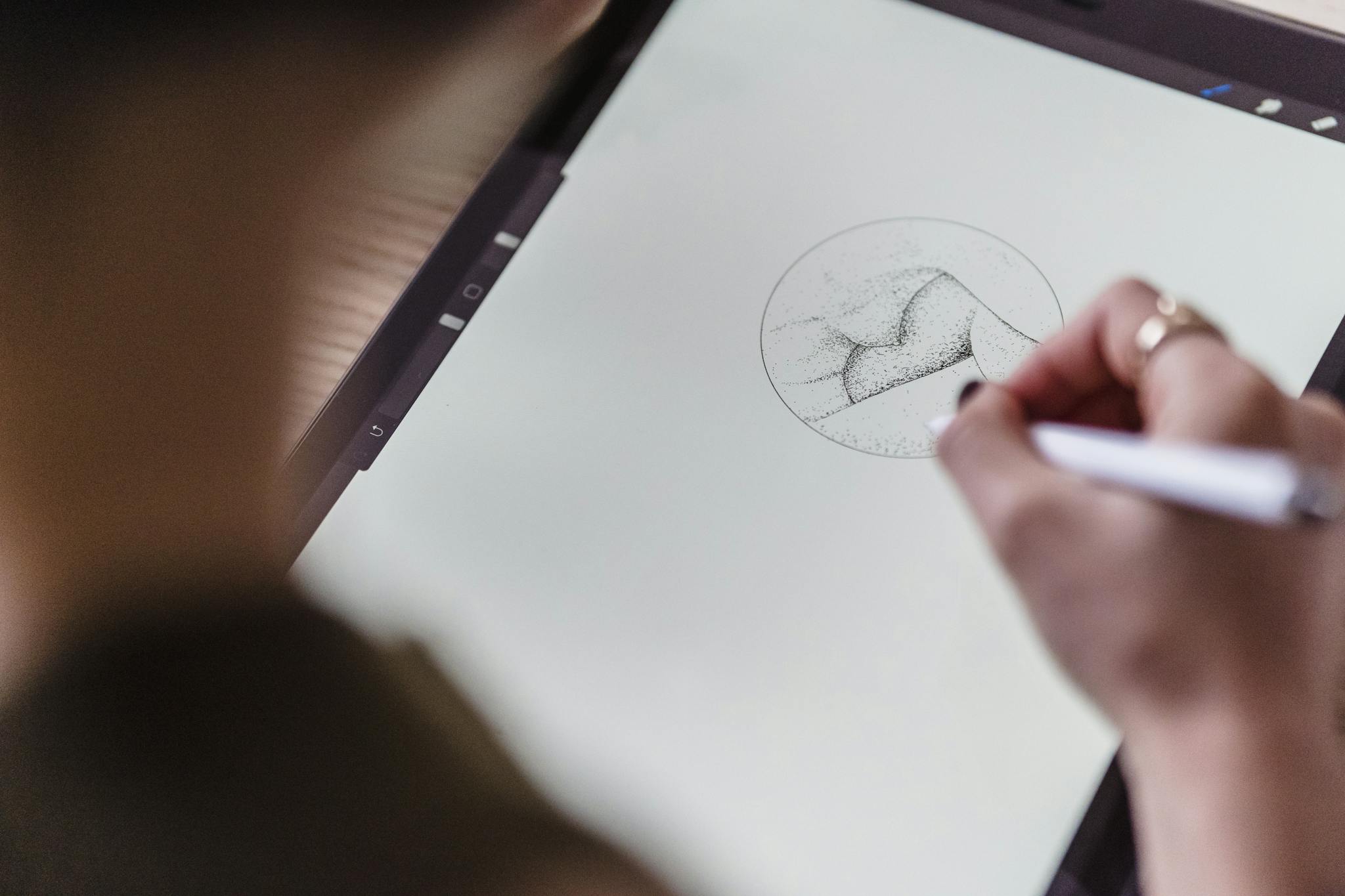 From above of crop anonymous artist with stylus in hand drawing creative sketch on graphics tablet